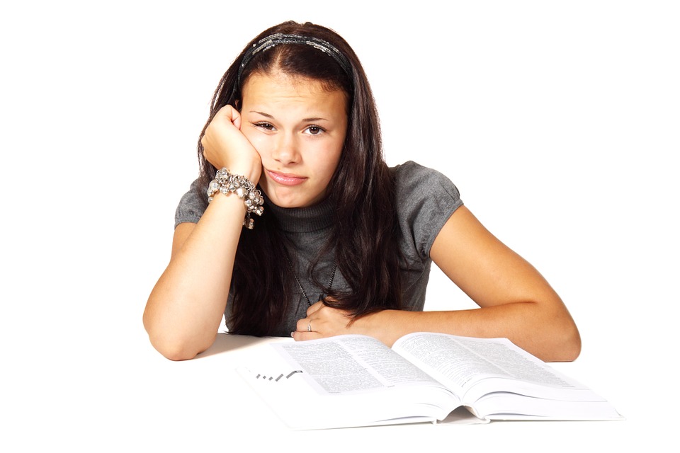 Schülerinnen sitzt vor einem Buch und sieht traurig aus, Credit: PublicDomainPictures, Pixabay