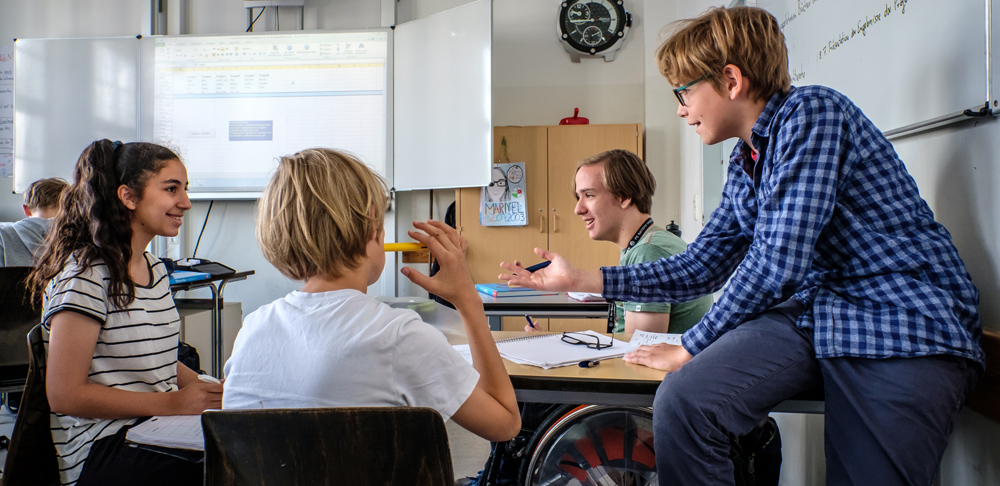 Gelebte Inklusion: Schülerinnen und Schüler im Teenageralter unterhalten sich in einem Klassenraum, Copyright: Andi Weiland | Gesellschaftsbilder.de