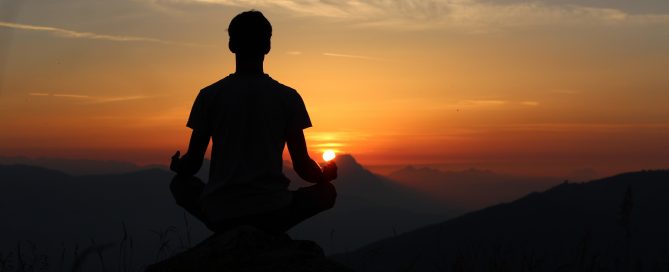Mann übt Yoga auf einem Berg bei Sonnenuntergang, Credit: Unsplash