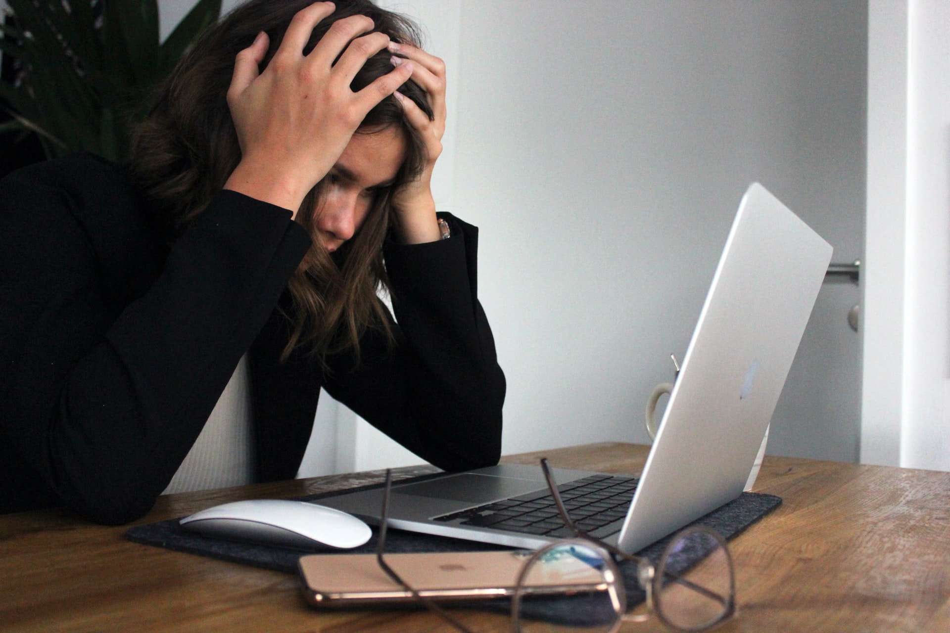 Symbolbild Fatigute: Frau stützt Kopf auf die Hände, während sie vor einem Laptop sitzt, Photo by Elisa Ventur on Unsplash