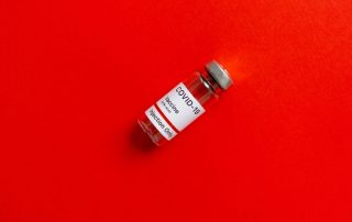 Covid-19-Impfserum auf rotem Hintergrund, Foto: Pexels