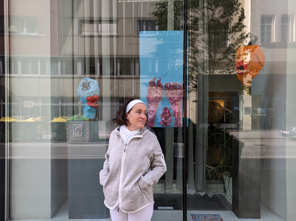 Die Künstlerin Sabin Jeanne vorm Beratungszentrum der MS Gesellschaft Wien, im Hintergrund einige der ausgestellten Exponate.